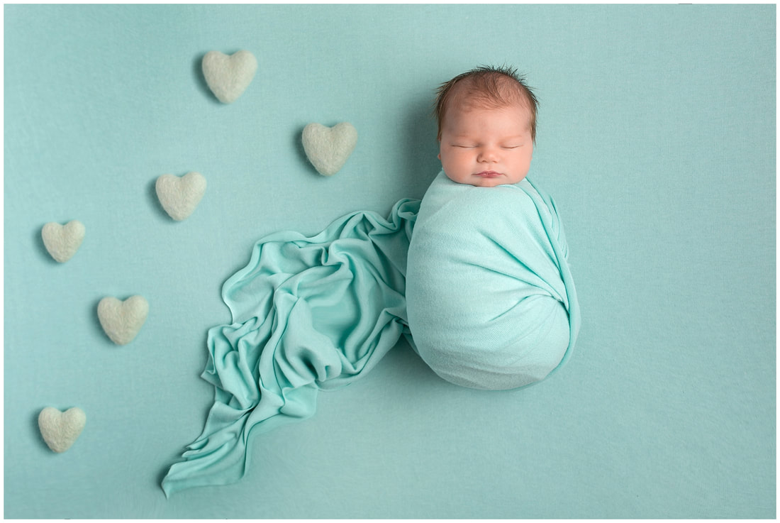 Newborn baby girl wrapped by Lynne Harper in aqua with hearts