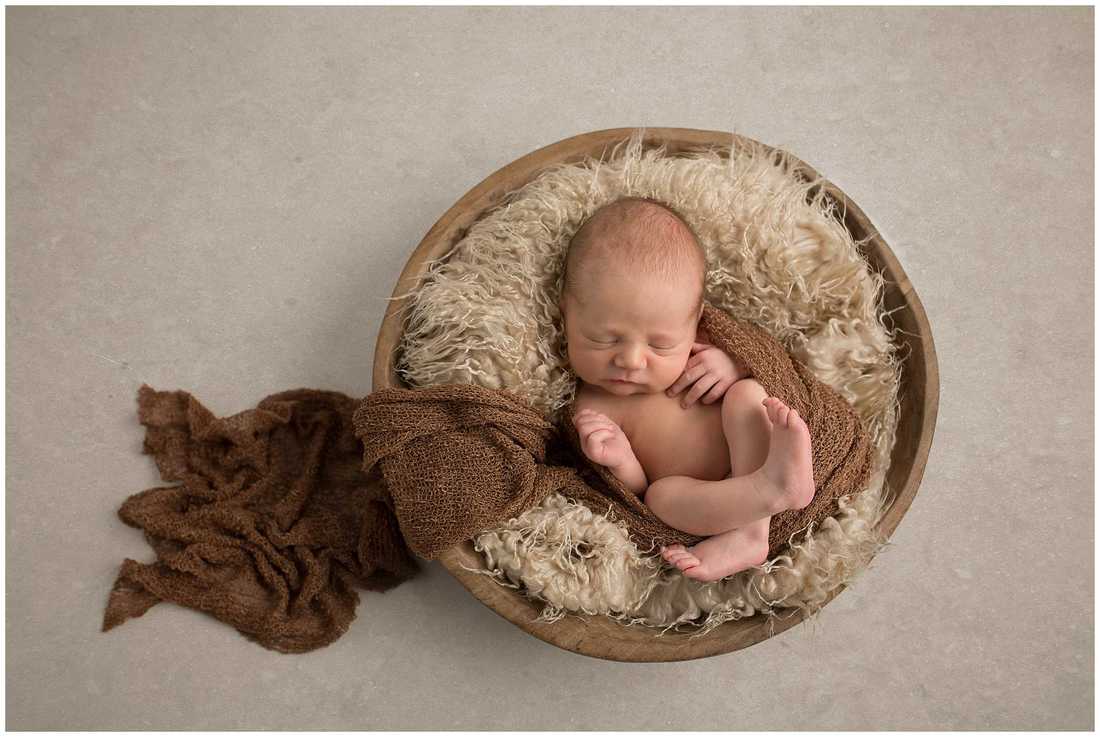 Picture of newborn baby boy in wooden bowl with brown wrap, posed by Lynne Harper Photography in Kilmarnock Ayrshire